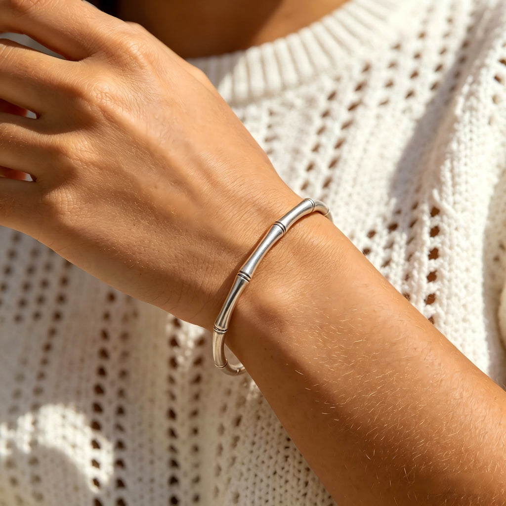 Silver bracelet on a wrist with a textured white sweater background