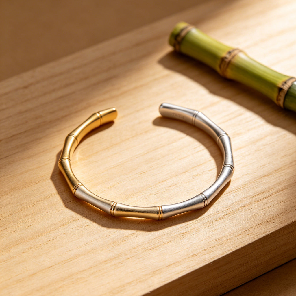 Gold and silver bracelet on a wooden surface with a bamboo stick.