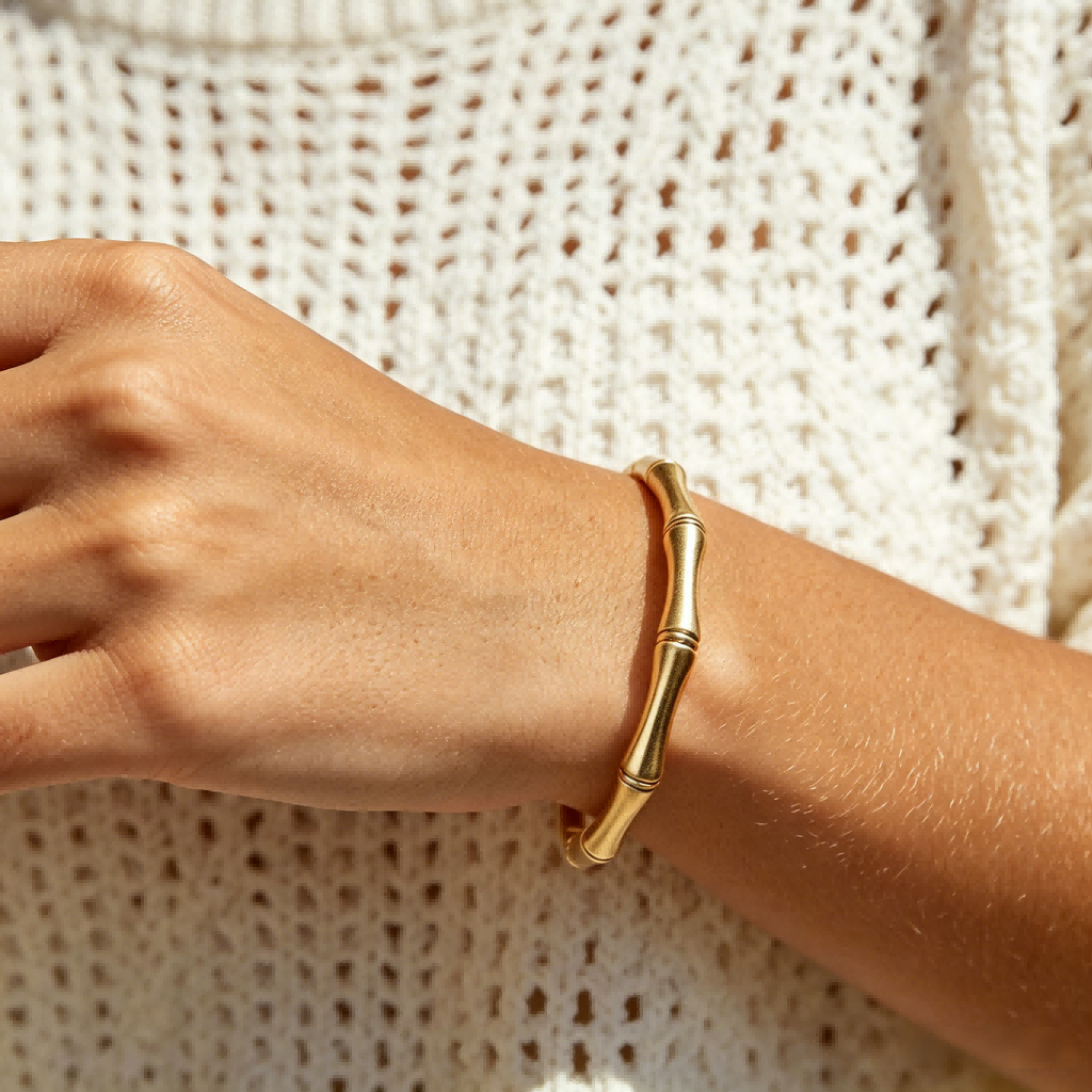 Gold bracelet on a wrist against a textured beige background