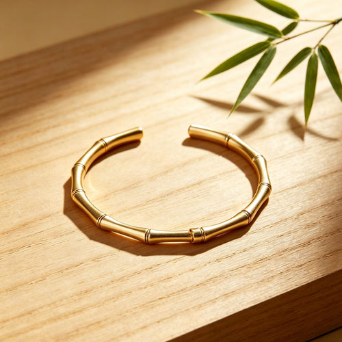 Gold bracelet on a wooden surface with a bamboo leaf